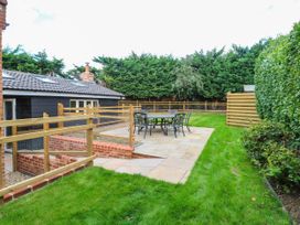A garden with a patio and table at Bramley Cottage in Worlingham