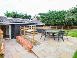 A garden with table and chairs near a house at Bramley Cottage in Worlingham