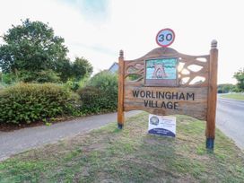 A village sign for Worlingham Village with surrounding greenery and road