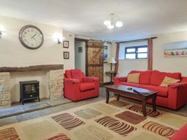 A living room with red sofas and a clock at Cider House in Hawkchurch
