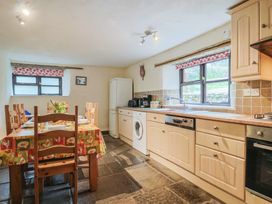 A kitchen with a dining table and wooden chairs at Cider House in Hawkchurch