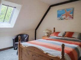 A bedroom with a bed and armchair at Cider House in Hawkchurch