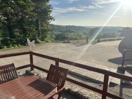 An outdoor area with a table and chair overlooking a landscape at Cider House in Hawkchurch