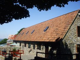 An outdoor view of a stone house with a tiled roof and windows at Cider House in Hawkchurch