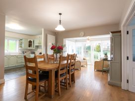 A dining room with a table and chairs leading to a sunroom at An Grianan Getaway Burt