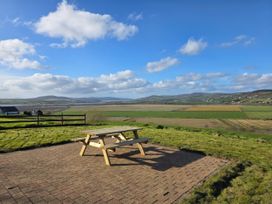 A picnic table on a patio with a view of fields and hills at An Grianan Getaway in Burt