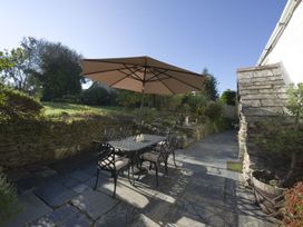 A garden with a table and chairs under an umbrella at Mays Cottage in Wadebridge