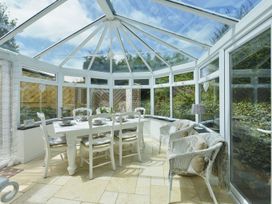 A conservatory with a dining table and chairs at Mays Cottage in Wadebridge