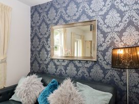 A living room with a mirror and a black sofa at Apartment 4 in Torquay