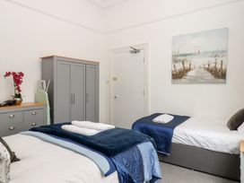 A bedroom with two beds and a wardrobe at Apartment 4 in Torquay