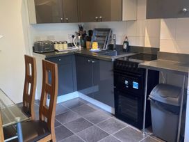 A kitchen with cabinets, stove, sink and dining table at Apartment 5 in Torquay