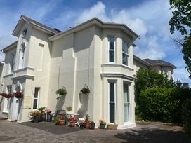 A white building with multiple windows and flower pots at Apartment 5 in Torquay