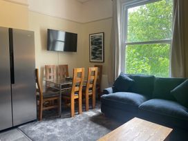 A living room with a dining table and chairs and a refrigerator at Apartment 5 in Torquay