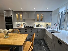 A kitchen with cabinets, stove, and dining table at La'al Kirkstone Brow in Ambleside