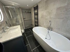 A bathroom with a bathtub, shower, sink, and towel radiator at La'al Kirkstone Brow in Ambleside