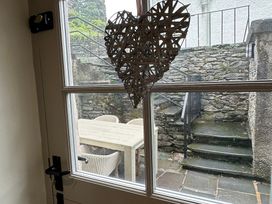 A window with a heart decoration looking out to an outdoor patio at La'al Kirkstone Brow in Ambleside