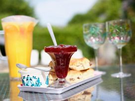 A table with orange juice, jelly, cream, scones, and decorative glasses at Apartment 9 in Torquay