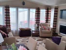 A living room with furniture including a sofa and armchair at B2 in Lossiemouth