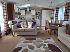 A living room with a sofa, table, and kitchen at B2 in Lossiemouth