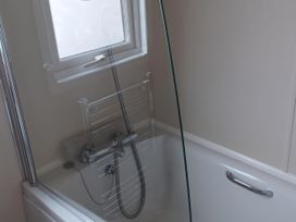 A bathtub with a glass shower screen and a showerhead at B2 in Lossiemouth