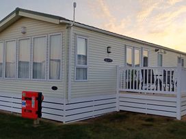 A mobile home with a deck and red box at Park Lake Vibe in Lossiemouth