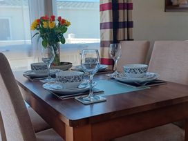 A dining room table set with dishes and a flower vase at B2 in Lossiemouth
