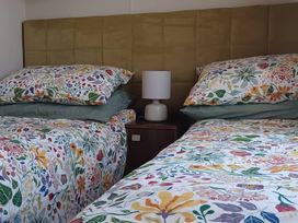 A bedroom with two beds and a lamp on a nightstand at B2 in Lossiemouth