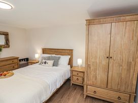 A bedroom with a bed, wardrobe, nightstand and mirror at Little Holm Garth