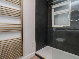 A bathroom featuring a shower, window, towel rack, and toilet at Little Holm Garth
