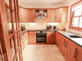 A kitchen with wood cabinets and appliances at Derwent Cottage in Cockermouth