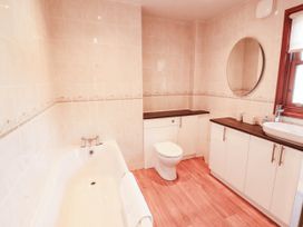 A bathroom with a bathtub, toilet, sink, and cabinet at Derwent Cottage in Cockermouth