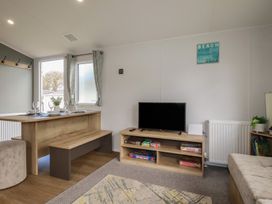 A living room with a table and television at Shamrocks Cove Caravan