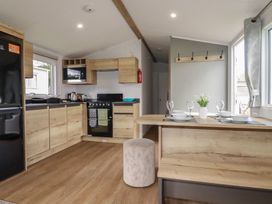 A kitchen with appliances and dining area at Shamrocks Cove Caravan