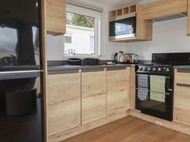 A kitchen with appliances and cabinets at Shamrocks Cove Caravan