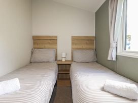 A bedroom with two beds and a bedside table at Shamrocks Cove Caravan