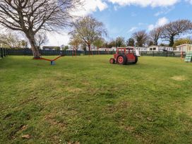 An outdoor play area with a swing set and a toy tractor at Shamrocks Cove Caravan