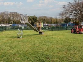 A slide and playground equipment in a grassy area at Shamrocks Cove Caravan