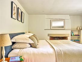 A bedroom with a bed, lamp, and shelf at Gitcombe Coach House in Totnes