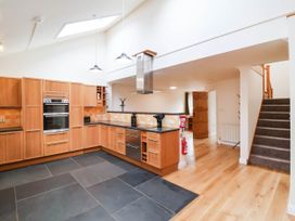 A kitchen with wooden cabinets and a staircase at The Station House Blackmoor Gate near Parracombe