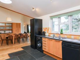 A kitchen with a refrigerator, washing machine, and dining area at The Station House Blackmoor Gate near Parracombe