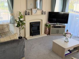 A living room with a television and a fireplace at Hoburne Blue Anchor - Holiday Accommodation 307 Minehead
