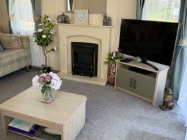 A living room with a sofa, television, and coffee table at Hoburne Blue Anchor - Holiday Accommodation 307, Minehead