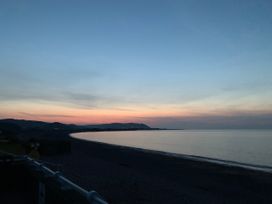 A beach at sunset with water and mountains at Hoburne Blue Anchor - Holiday Accommodation 307 Minehead