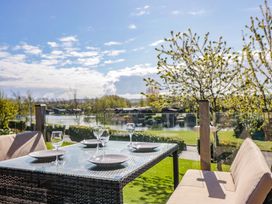 An outdoor dining setup with table and chairs overlooking a lake at Borwick Heights 17 Carnforth