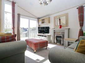 A living room with a television and a fireplace at Borwick Heights 17 in Carnforth