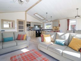 A living room with sofas and kitchen area at Borwick Heights 17 in Carnforth