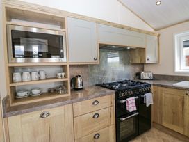 A kitchen with a microwave, kettle, and cooking range at Borwick Heights 17 in Carnforth