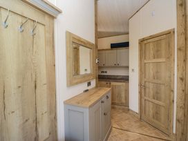 A hallway with a cabinet, mirror and hooks at Borwick Heights 17 Carnforth