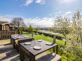 An outdoor dining area with a table and chairs overlooking a lake at Borwick Heights 17, Carnforth