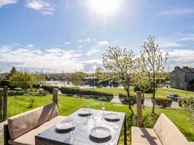A garden with a dining table and chairs overlooking a lake at Borwick Heights 17 in Carnforth